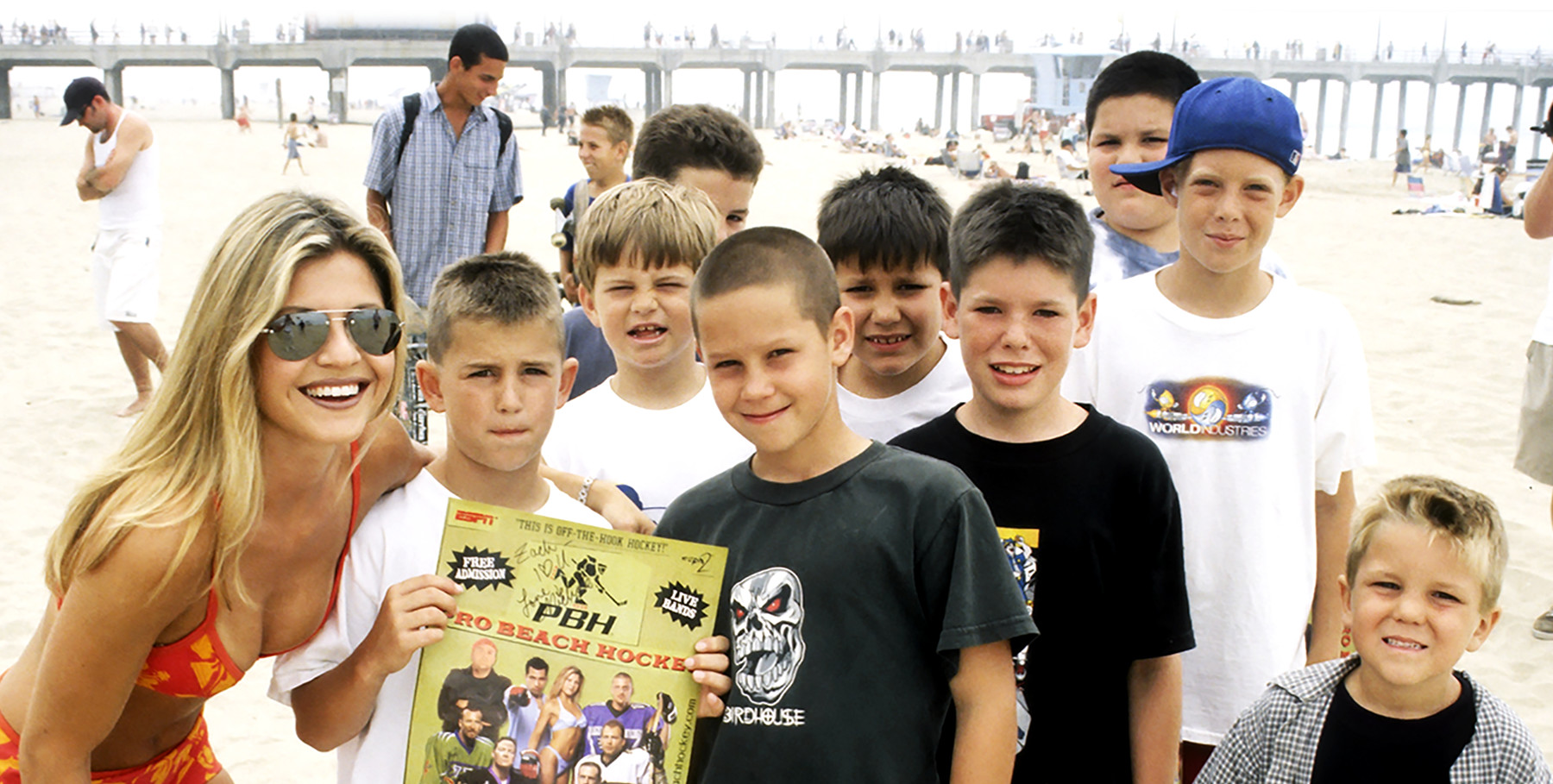 Group of kids with a poster and an adult at a Pro Beach Hockey event on the beach